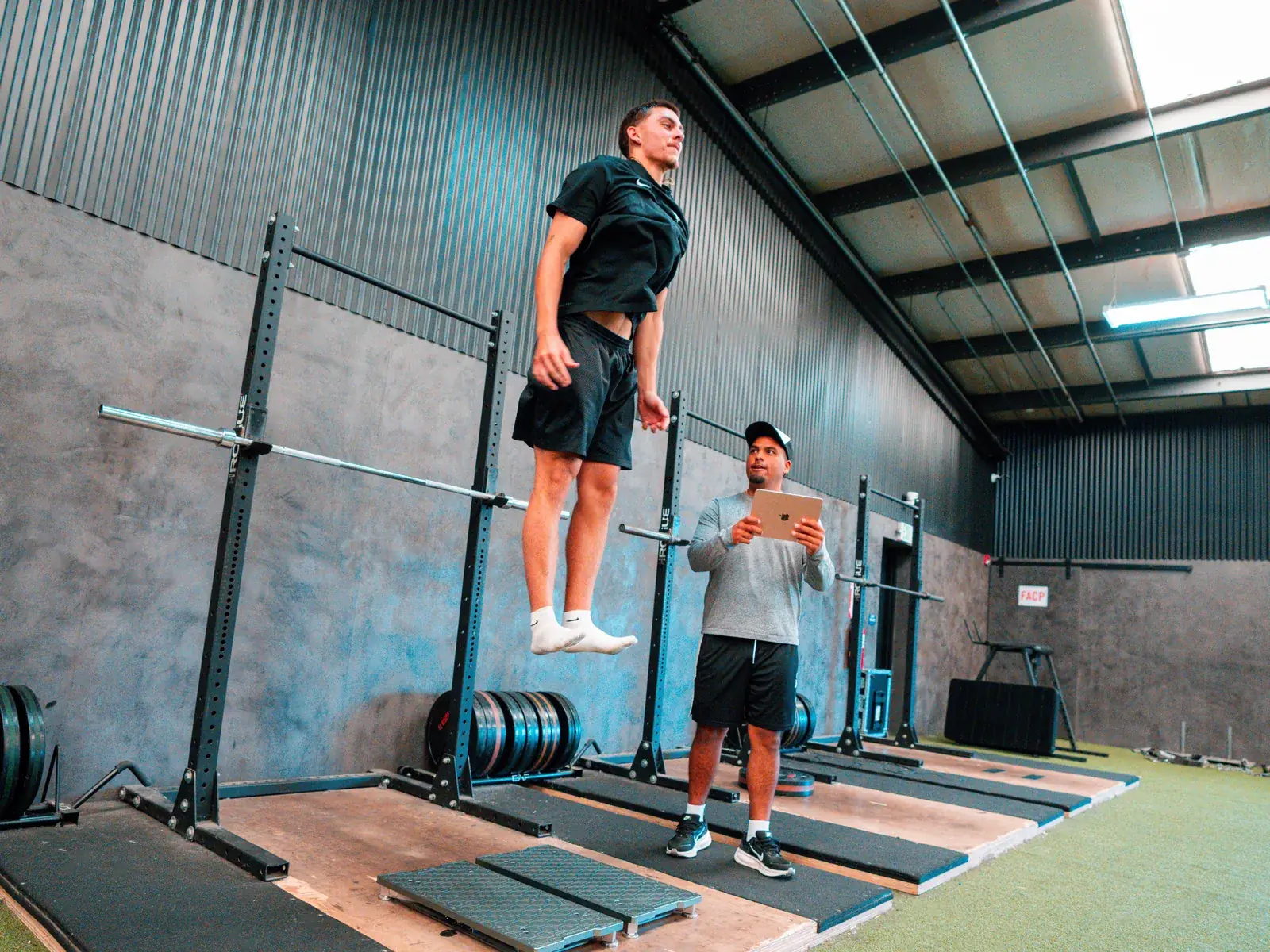 Athlete jumping on force plates while a coach records the result on a tablet